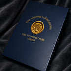 Dark blue book with gold embossed text and emblem on a black fabric background